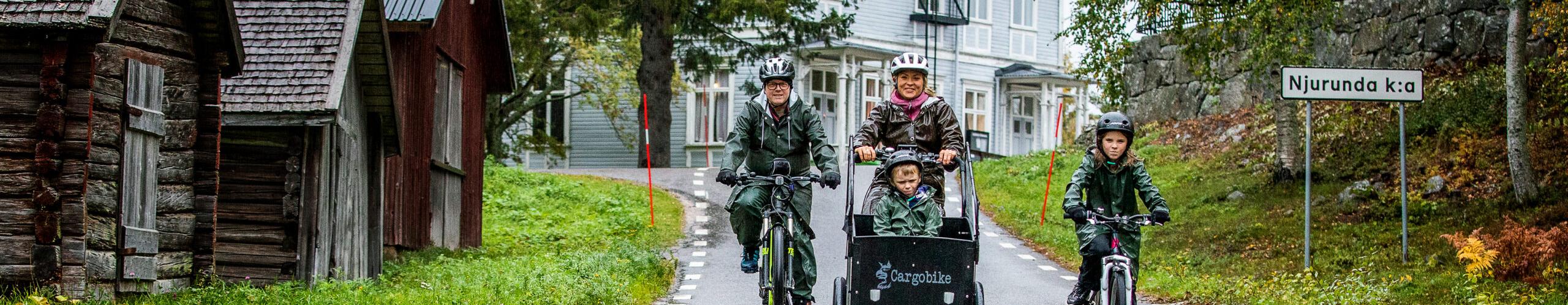 En familj cyklar på cyklar längs en väg. 